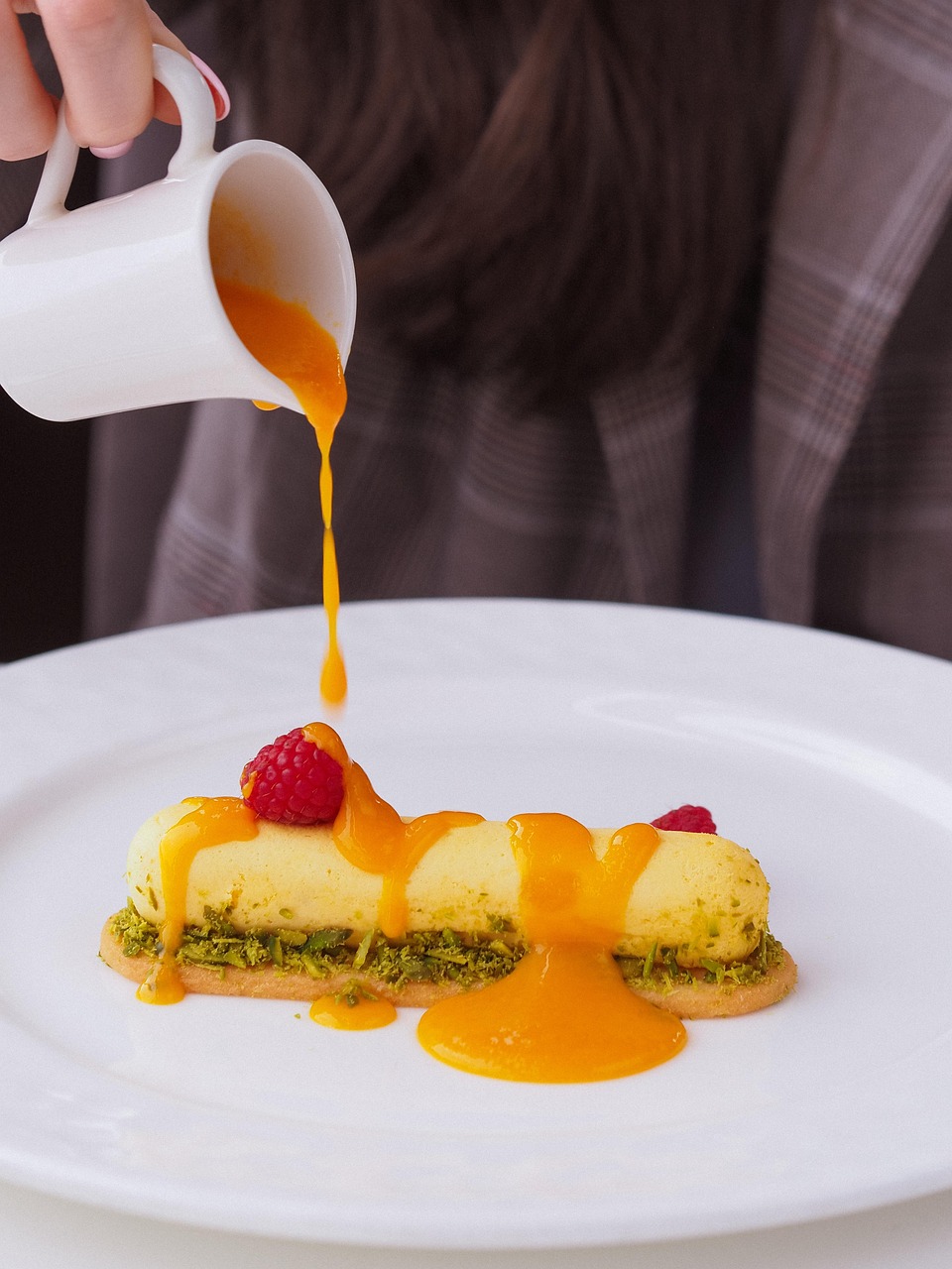 person pouring sauce over dessert